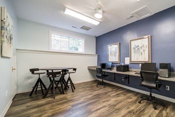 a room with a desk with computers and a table with chairs